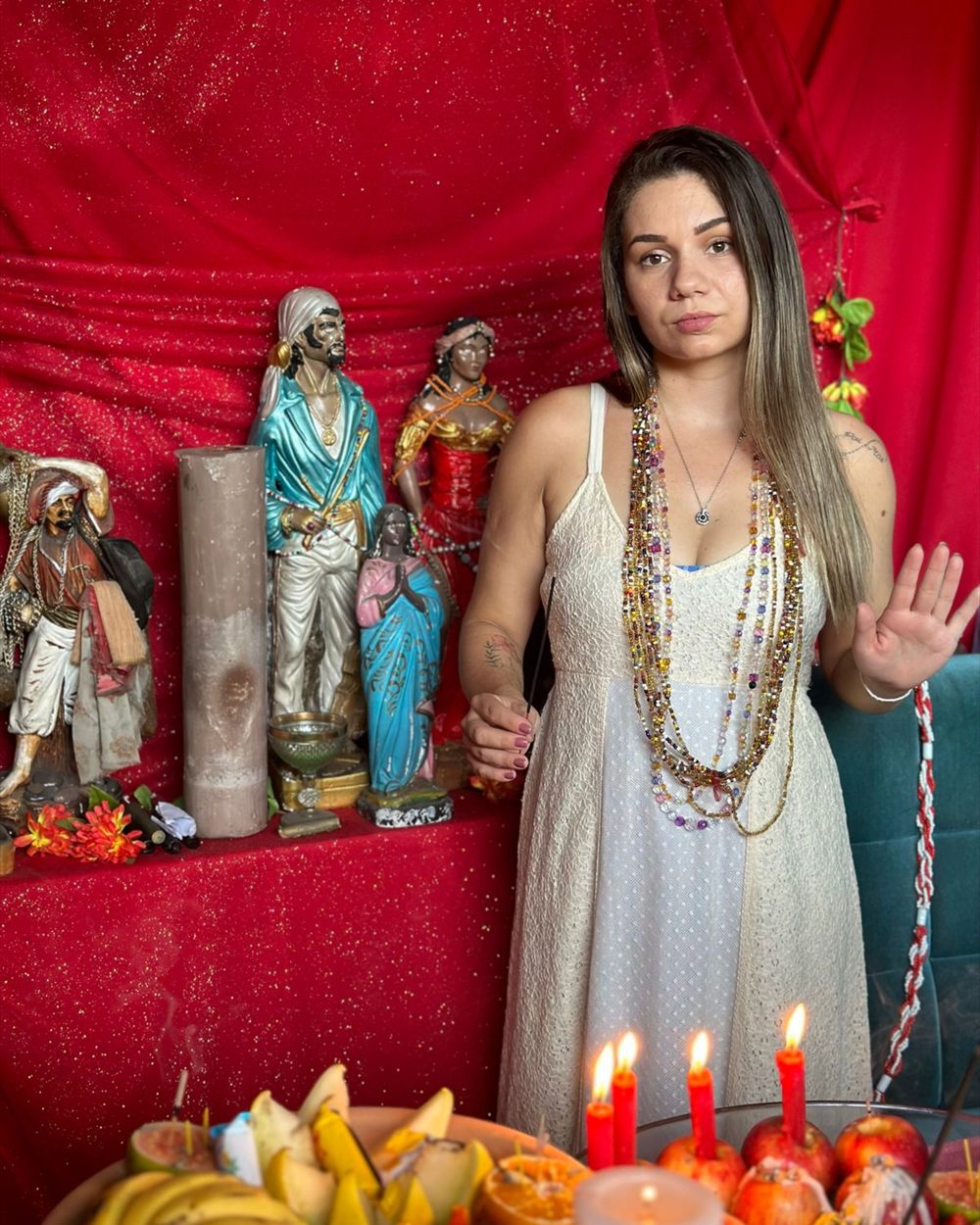 Isabel de Oxóssi diante do altar, com as guias no pescoço